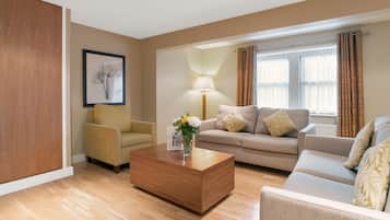 A modern living room with a wooden coffee table, a beige sofa, and a yellow armchair.