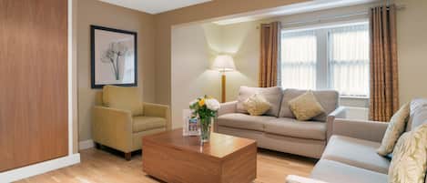 A modern living room with a wooden coffee table, a beige sofa, and a yellow armchair.