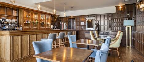 A bar area with wooden paneling, bar stools, and a counter with various bottles and glasses.