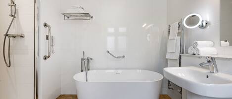 Un baño moderno con una bañera independiente, ducha a ras de suelo y un lavabo con espejo.