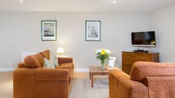 A living room with two brown sofas, a coffee table, a TV, and framed pictures on the wall.