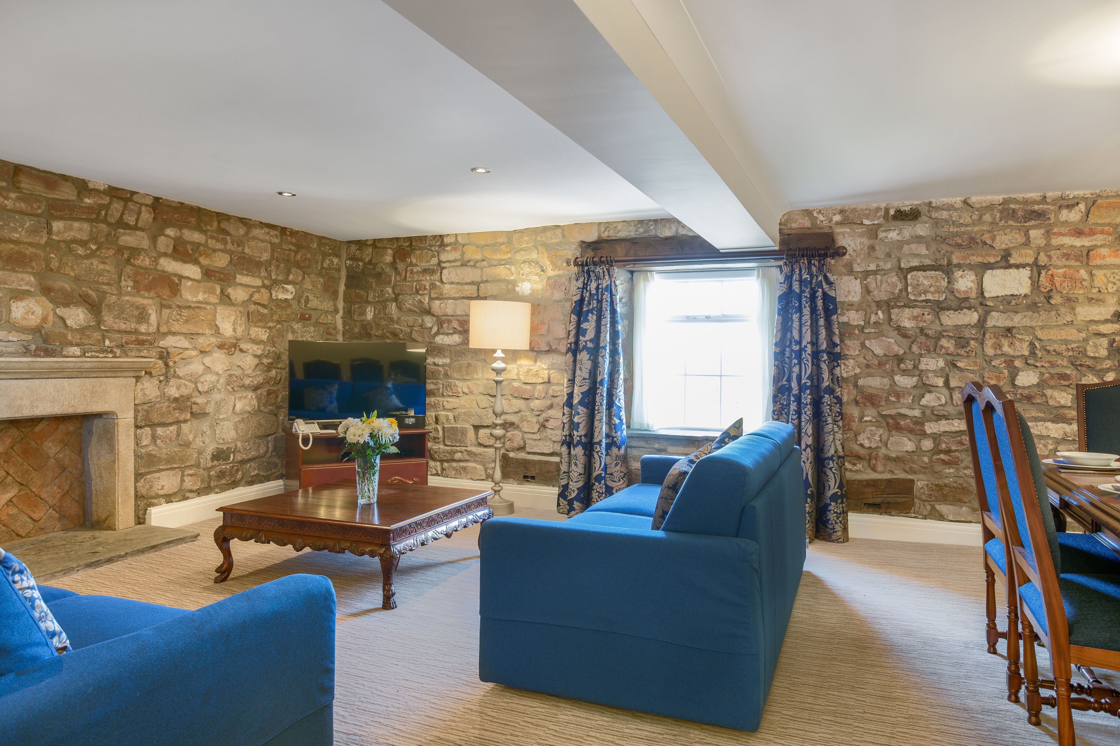Una sala de estar con pared de piedra, chimenea, sofá y televisor.