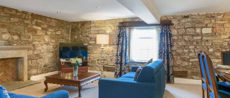 A living room with a stone wall, a fireplace, a sofa, and a television.
