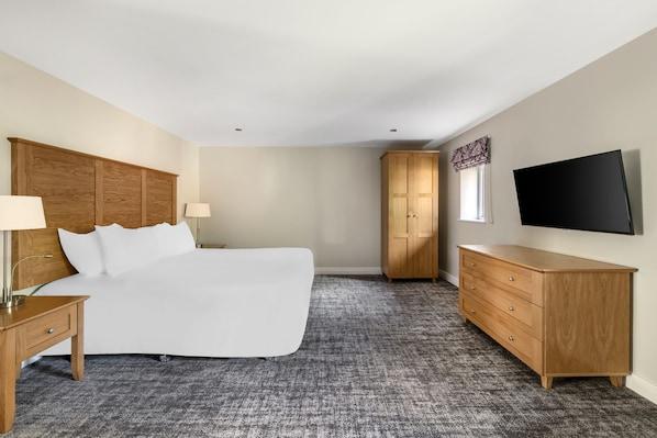 A hotel room with a large bed, wooden headboard, a dresser, a television, and a wardrobe. - Thurnham Hall Resort (Lancaster)