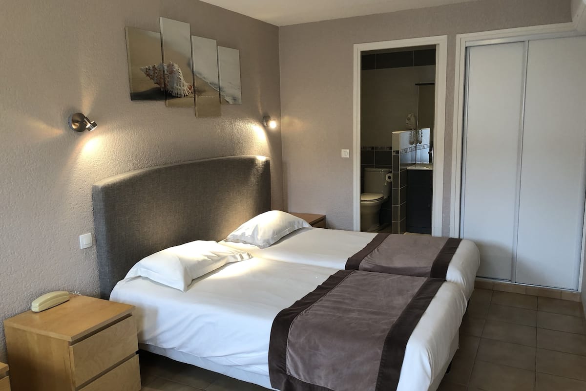 Una camera d'albergo con un letto grande, comodini, un telefono e un bagno visibile attraverso una porta aperta.