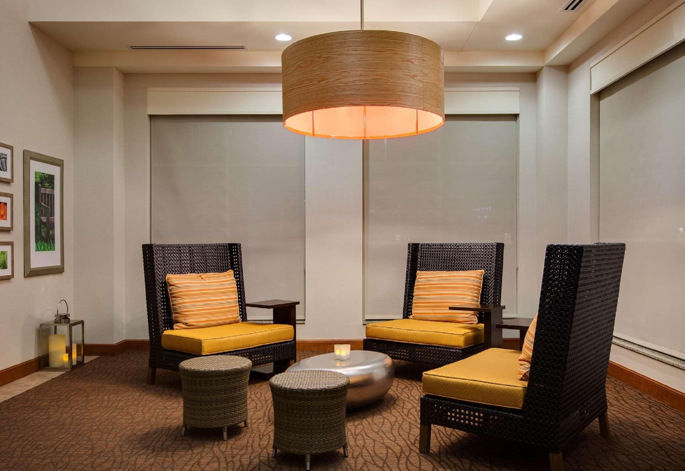 Un espace de détente moderne, avec des meubles en osier, une table ronde centrale et un luminaire suspendu.