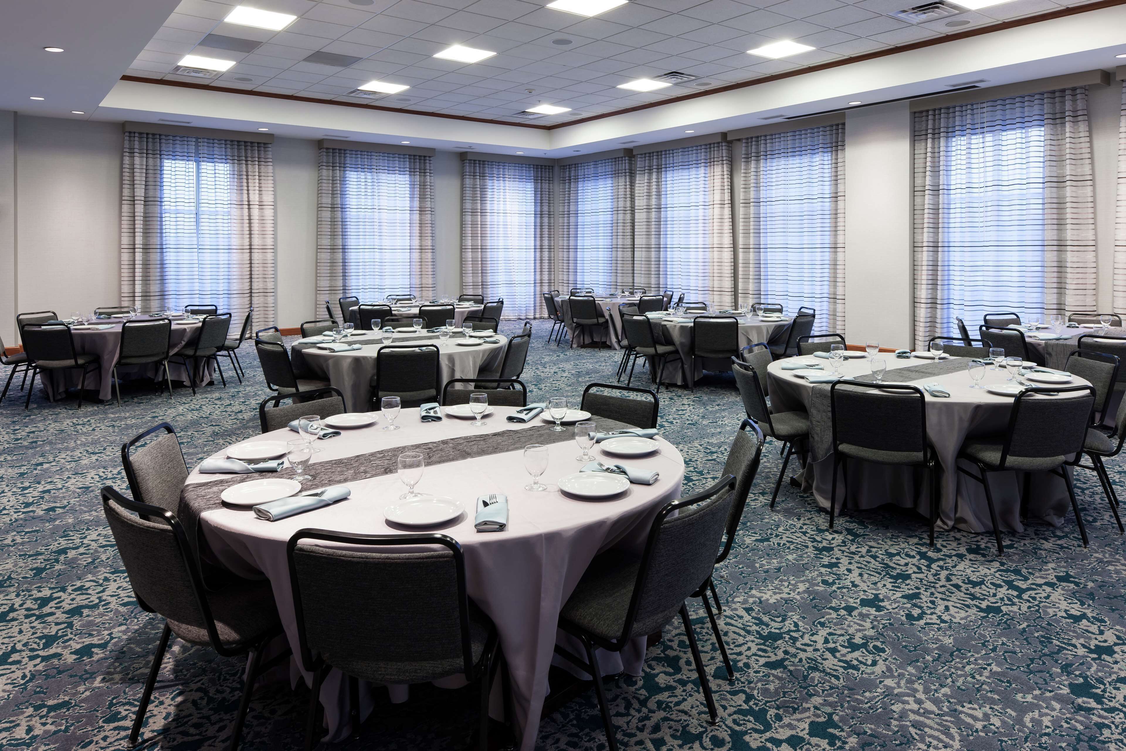 A conference room with round tables, chairs, and a carpeted floor.