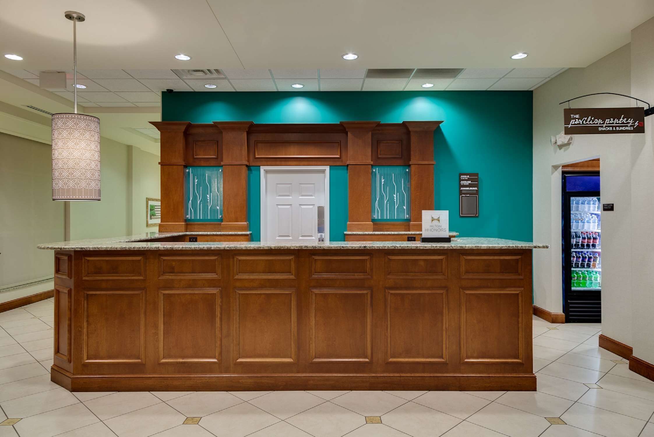Una zona de recepción con un mostrador de madera, paredes color azul verdoso y una puerta.