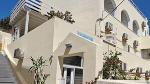A building with a white facade, multiple balconies, and air conditioning units. - Anemomilos Villa (Santorini)