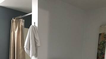 A bathroom with a shower curtain, a toilet, and a towel rack with two towels.