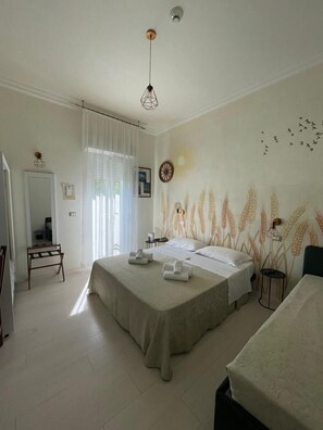 A hotel room with a large bed, a desk, and a chair. There is a window with curtains, a wall clock, and a wall with wheat patterns. - Hotel Dei Platani (Rimini)
