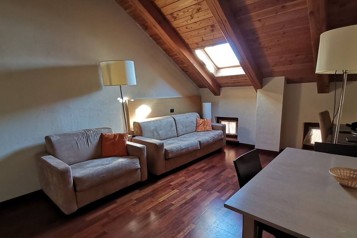 Une pièce confortable de style loft, avec un plafond en bois, un canapé, une table et une lampe.