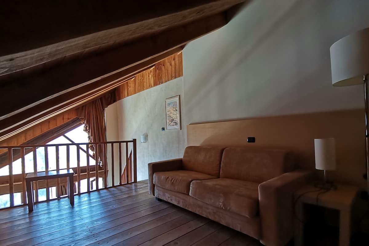 Une pièce chaleureuse avec un plafond en bois, un canapé marron, une table et une lampe.