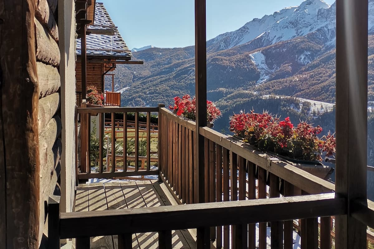 Un balcon en bois offrant une vue sur des montagnes enneigées.