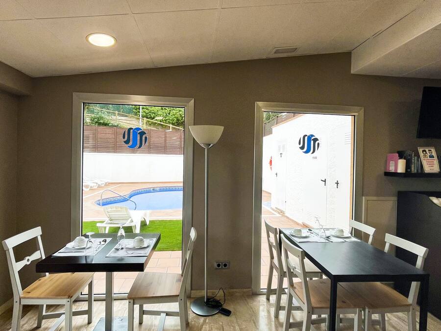 Un comedor con vista a la piscina, un televisor de pantalla plana y una estantería.