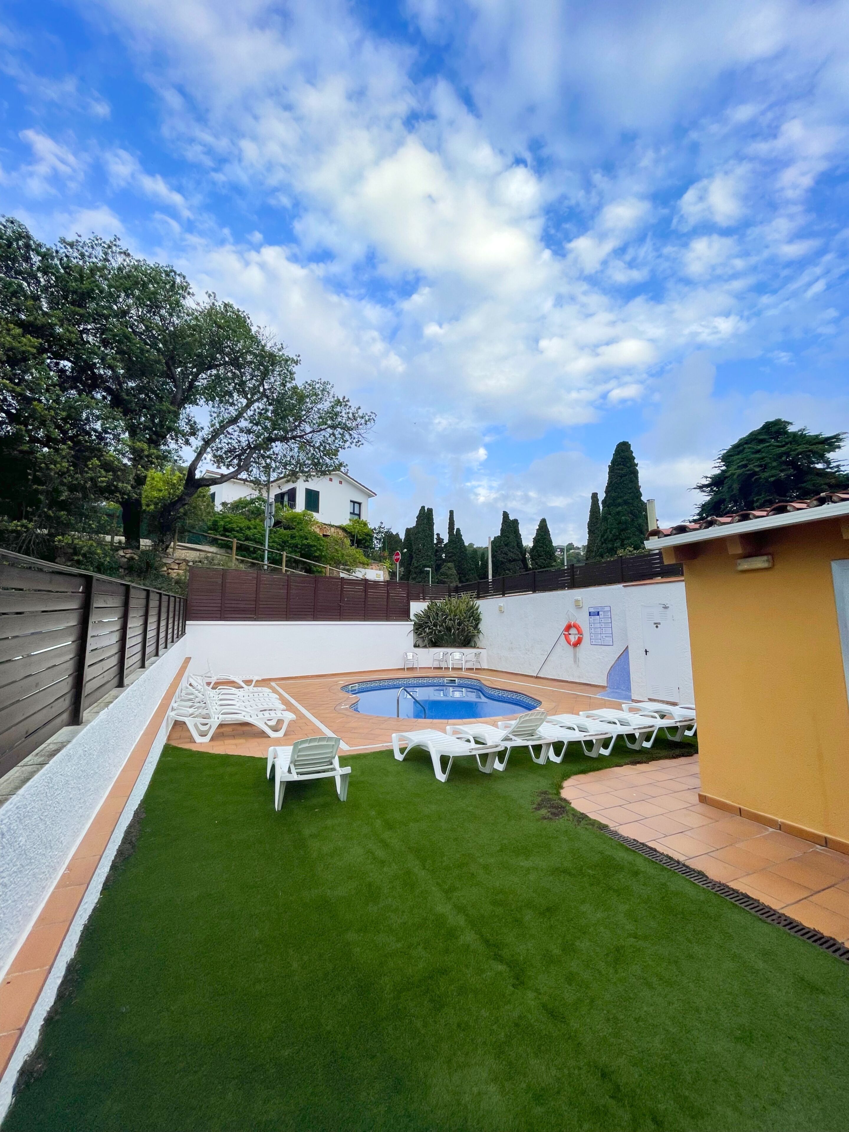 Un giardino sul retro con piscina, poltrona da relax bianca e prato ben curato.