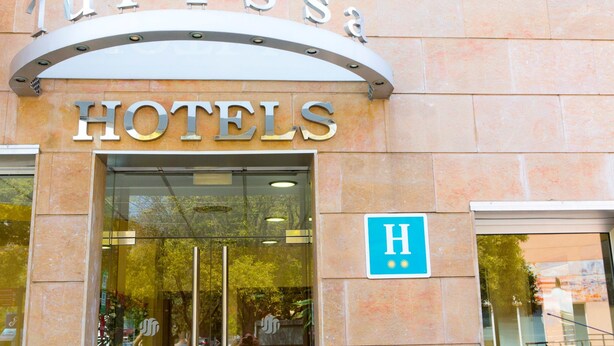 L’entrée d’un hôtel, avec une enseigne indiquant « Turissa Hotels » et un panneau bleu signalant l’accessibilité aux personnes handicapées.
