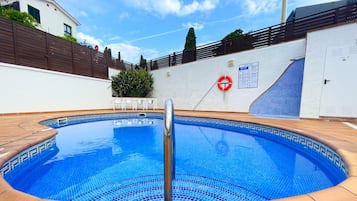 A swimming pool with a tiled edge, a lifebuoy, and a stop sign on a fence.