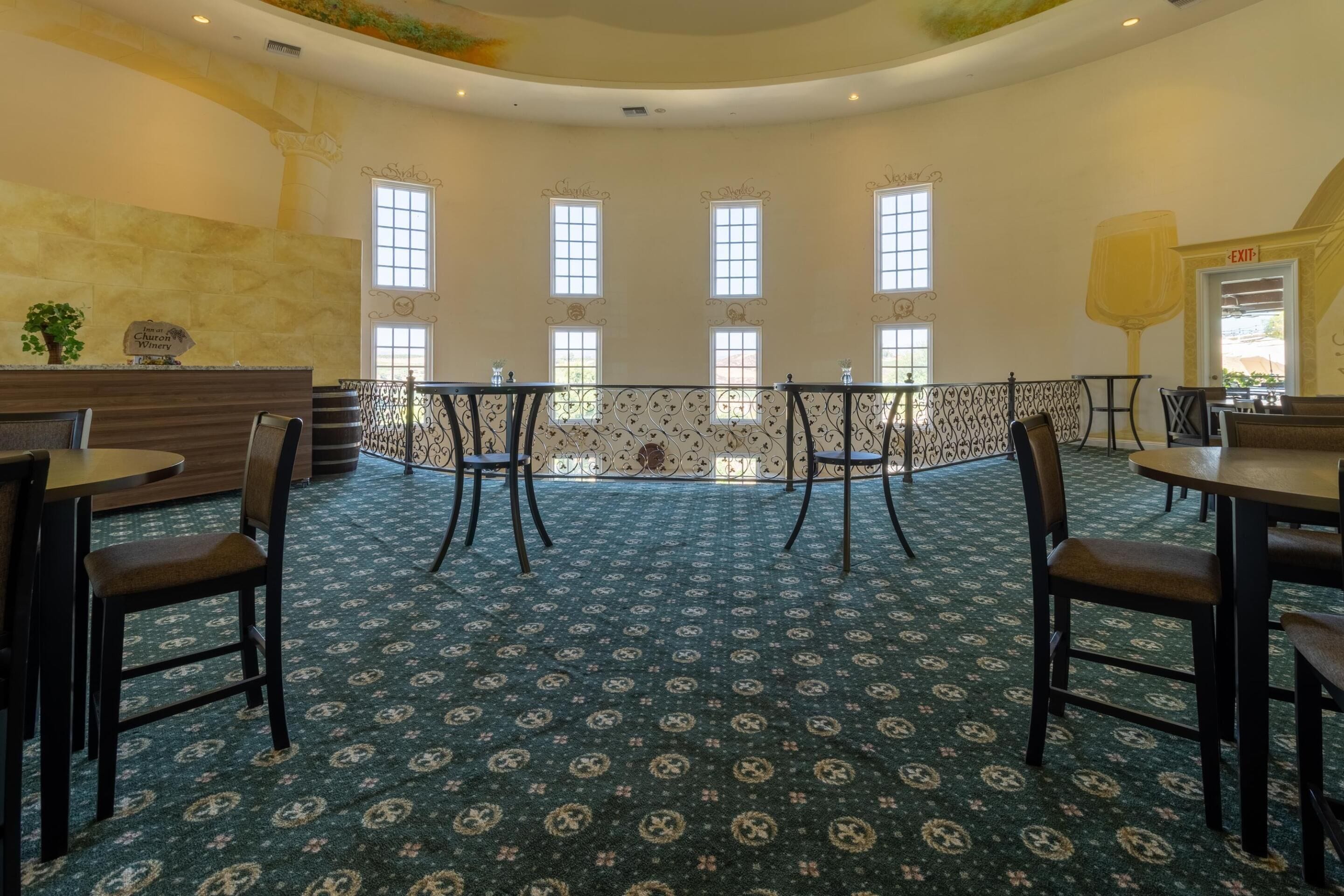 Une pièce spacieuse dotée d’un tapis à motifs, d’un comptoir d’accueil et offrant une vue sur l’extérieur grâce à de grandes fenêtres.