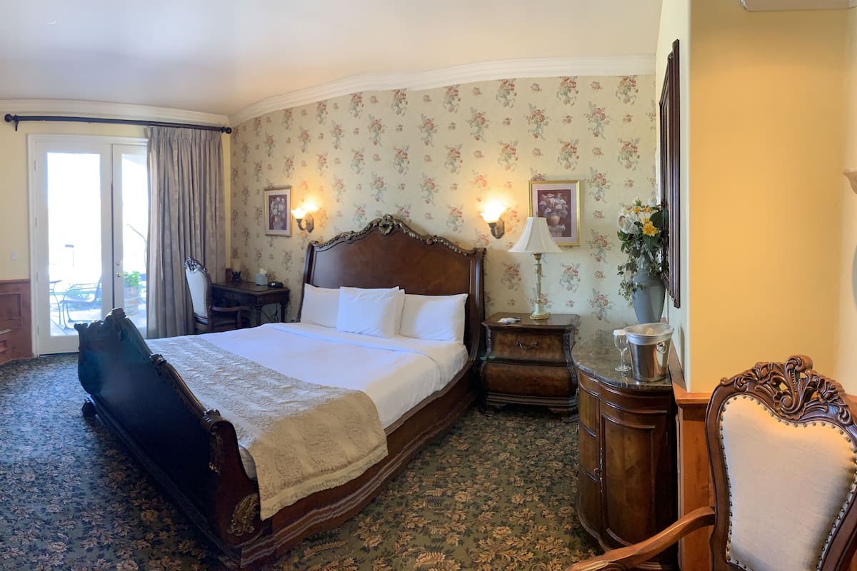 Una habitación de hotel con una cama grande, un escritorio, una silla, un aparador, un televisor y una chimenea.