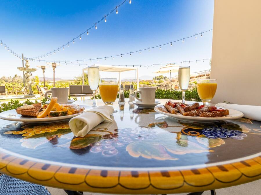 A table set for breakfast with plates of food, glasses of orange juice, and a pitcher of water.