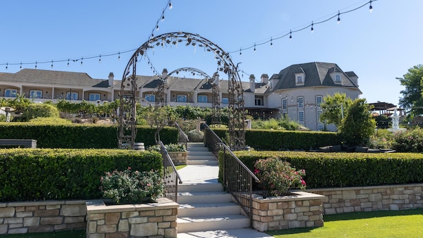 A residential property with a well-maintained garden, a stone staircase leading to the entrance, and string lights overhead.