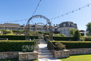 Una propiedad residencial con un jardín bien cuidado, una escalera de piedra que lleva a la entrada y luces decorativas colgando.