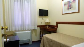 Une chambre d’hôtel équipée d’un lit, d’un bureau, d’une chaise, d’un téléviseur fixé au mur et d’un radiateur.