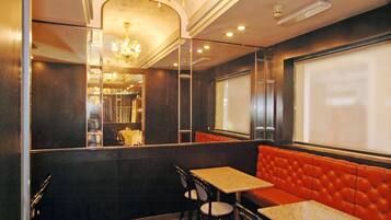 Un restaurante con una cabina tapizada de rojo, una mesa con sillas y un candelabro.