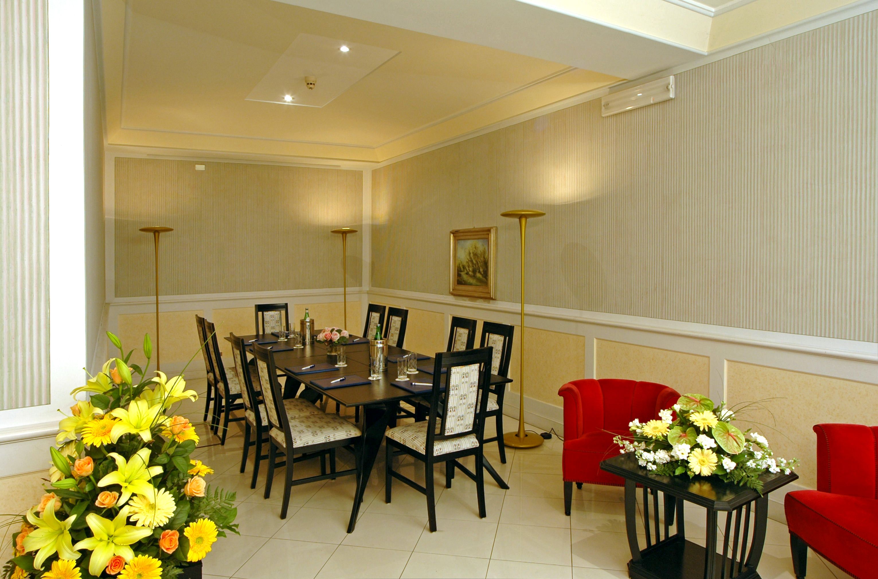 Un coin repas avec une table dressée pour six personnes, entourée de chaises, et un canapé rouge.
