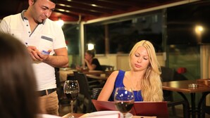 A restaurant setting with tables, wine glasses, and a menu.