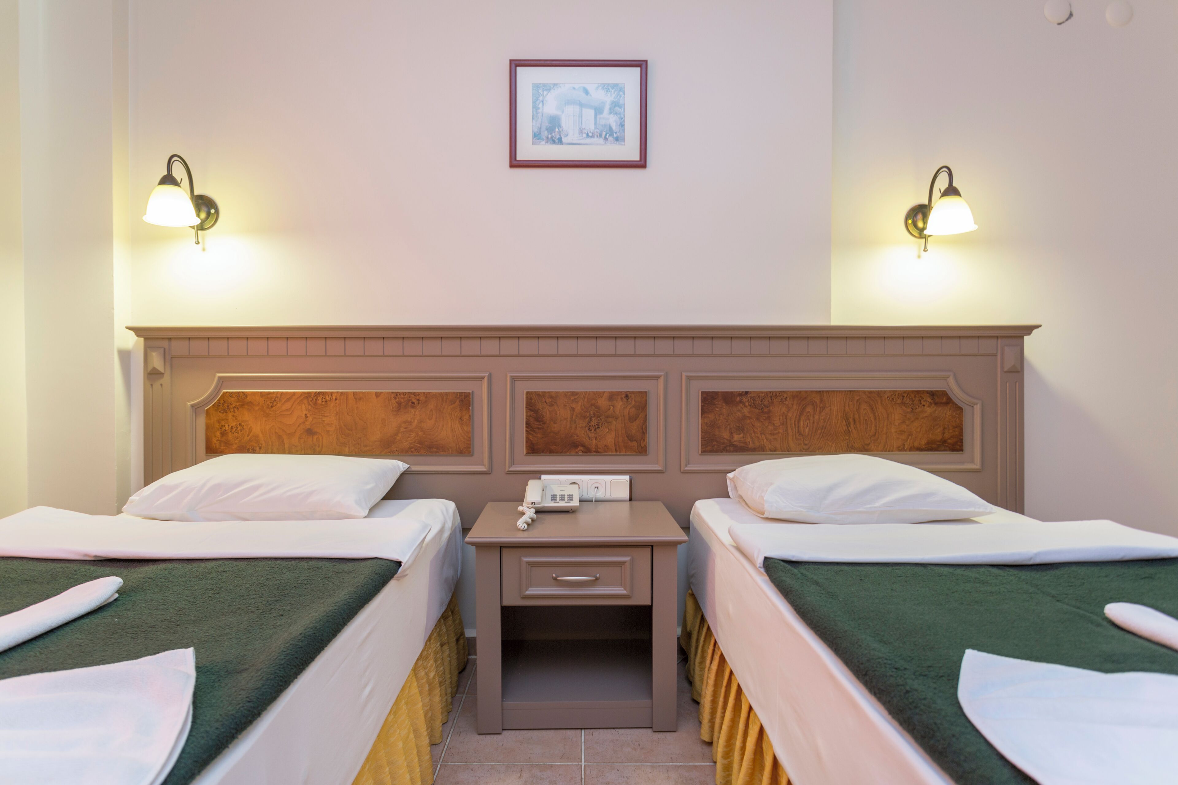 Una habitación de hotel con dos camas, una mesita de noche y un cuadro en la pared.