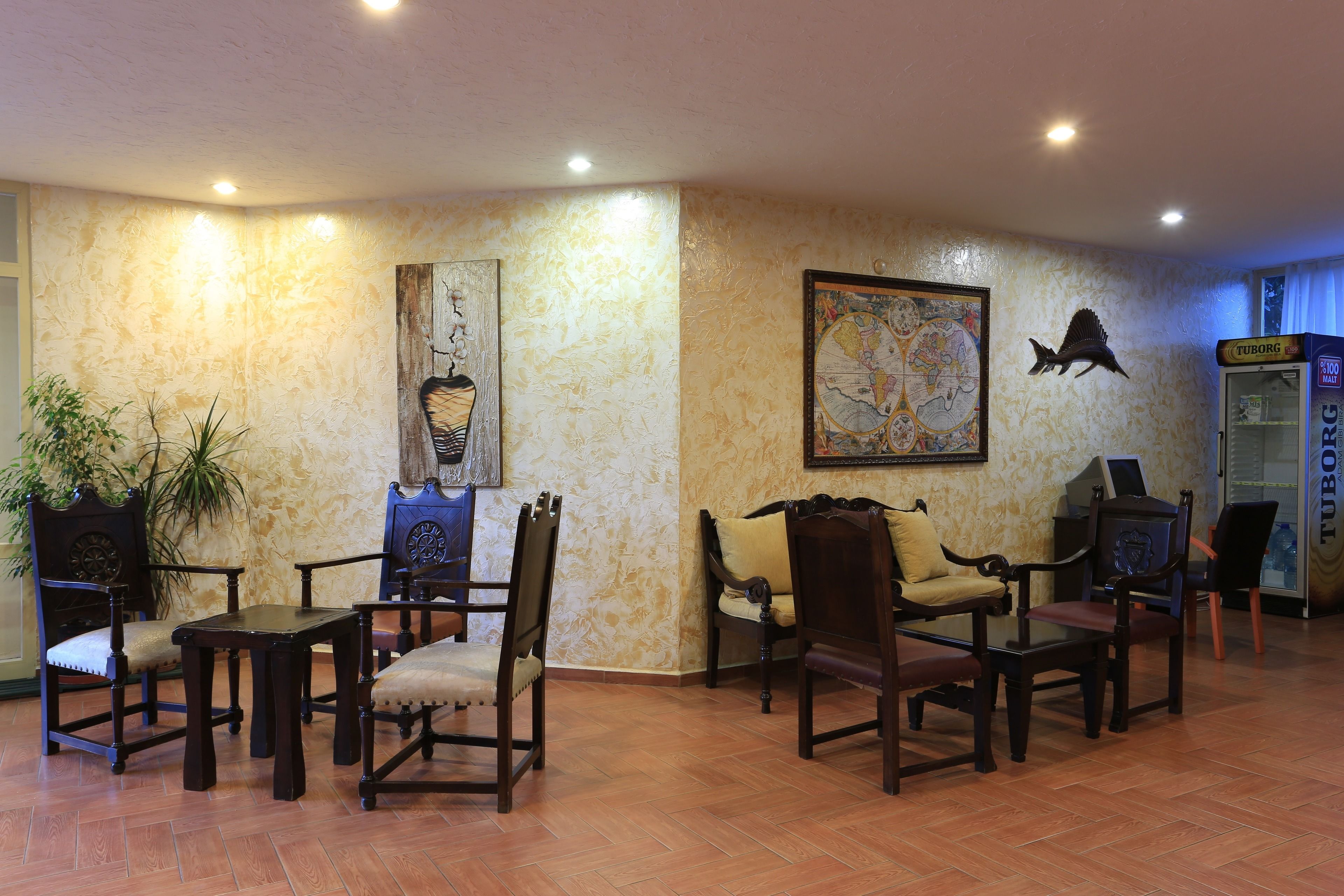 A lobby with wooden chairs and tables, a globe, and a vending machine.