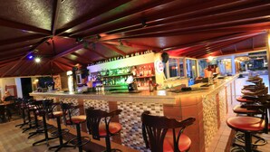 A bar area with a counter, stools, and a tiled floor.