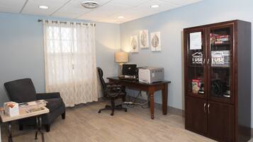 Una habitación con escritorio, silla de oficina, computadora, lámpara y un mueble con objetos.