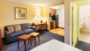 A hotel room with a sofa, a small table, a bed, a kitchenette, and a bathroom visible through an open door. - MainStay Suites Dover (Dover)