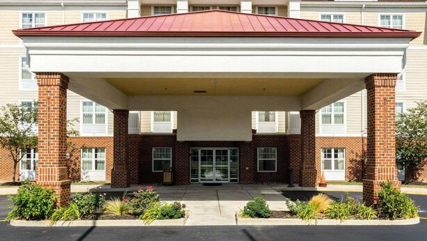 A MainStay Suites hotel with a covered entrance, brick facade, and a clear blue sky. - MainStay Suites Dover (Dover)