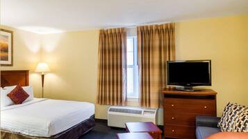 A hotel room with a bed, a desk, a television, a dresser, and a chair.