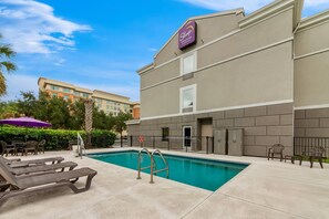 A hotel with a swimming pool, outdoor seating, and a sign for 'Sleep Inn & Suites by Choice Hotels'.