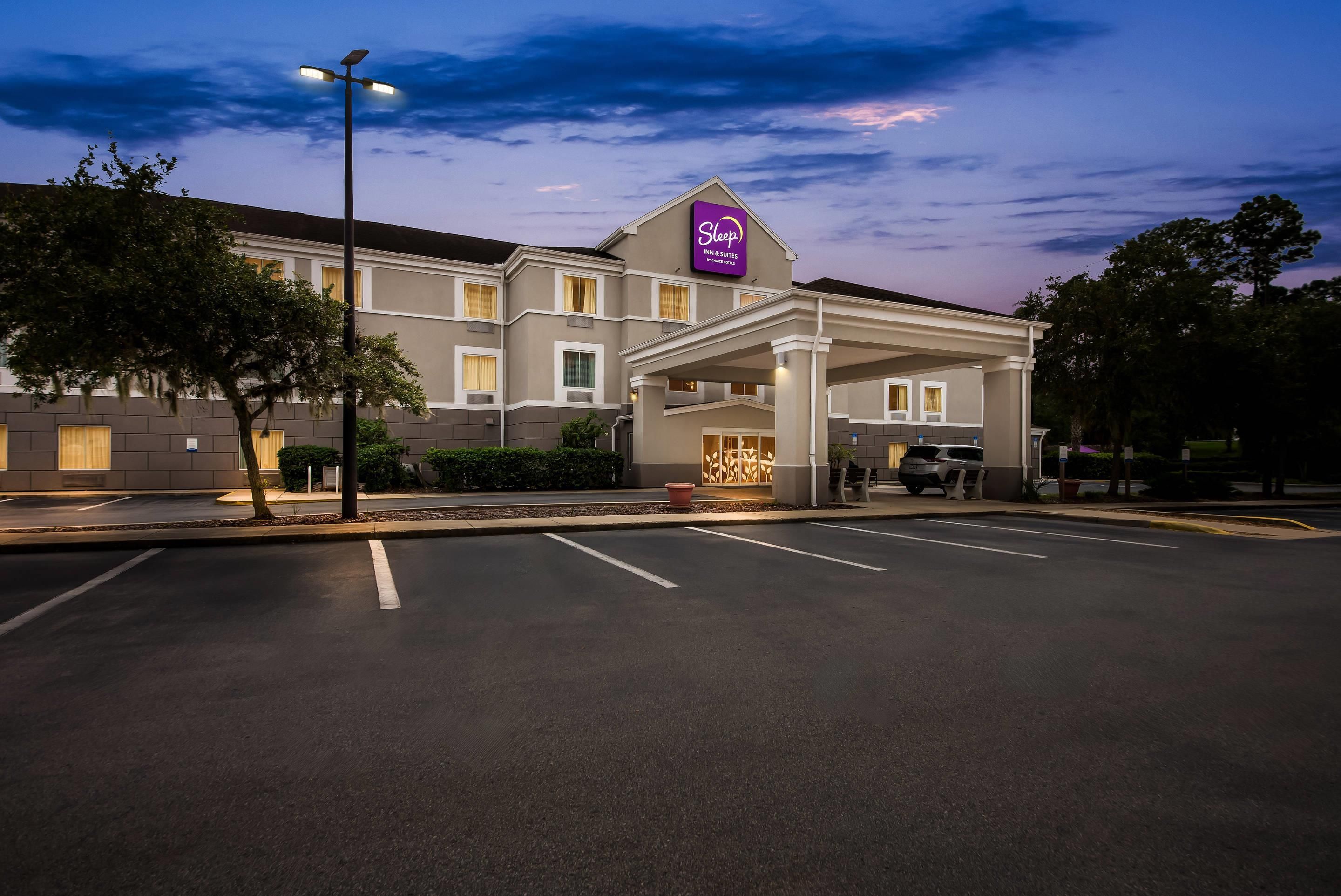 Un hotel con una entrada destacada, una cartelera y un estacionamiento.