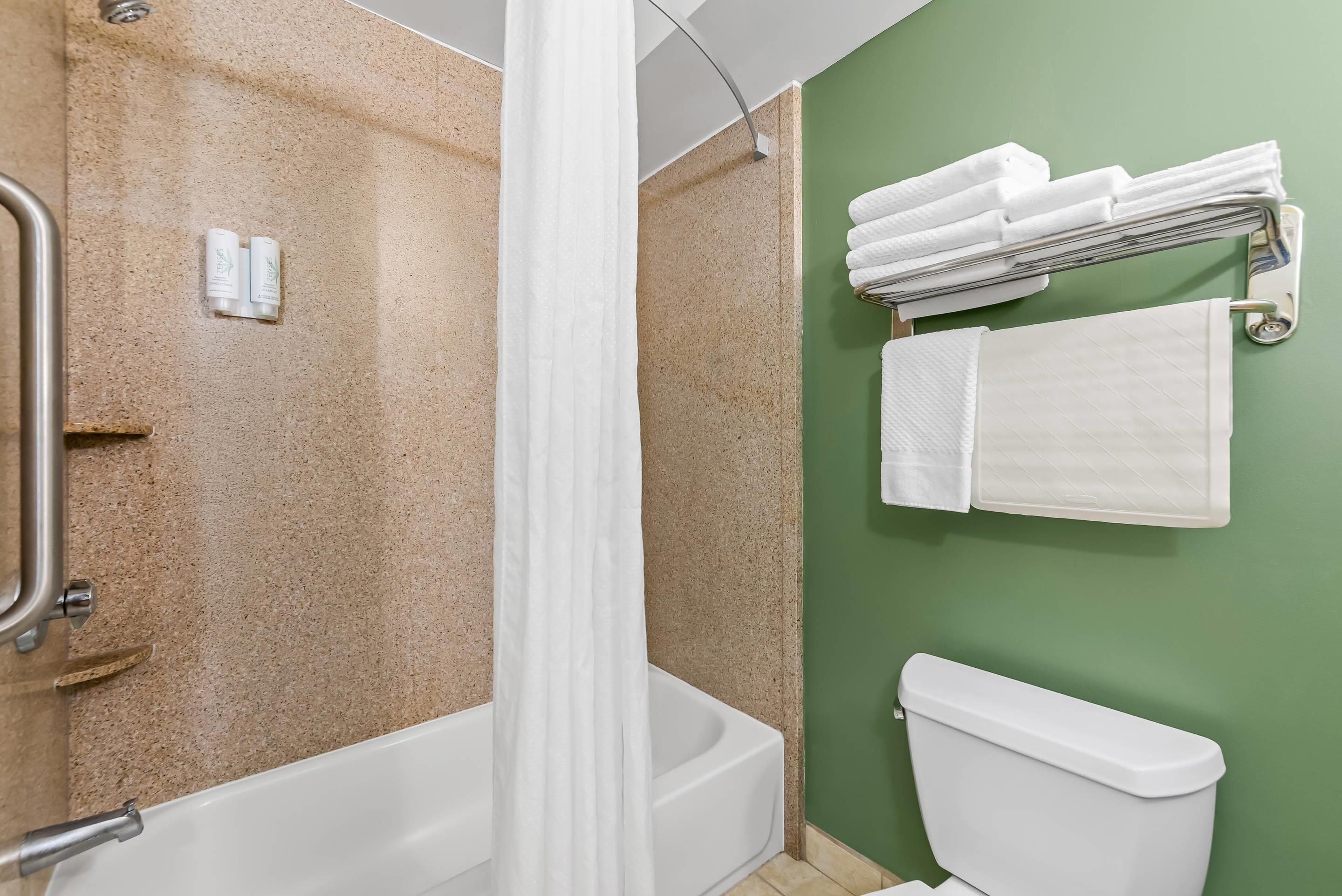 Un baño con ducha, inodoro y toallero.
