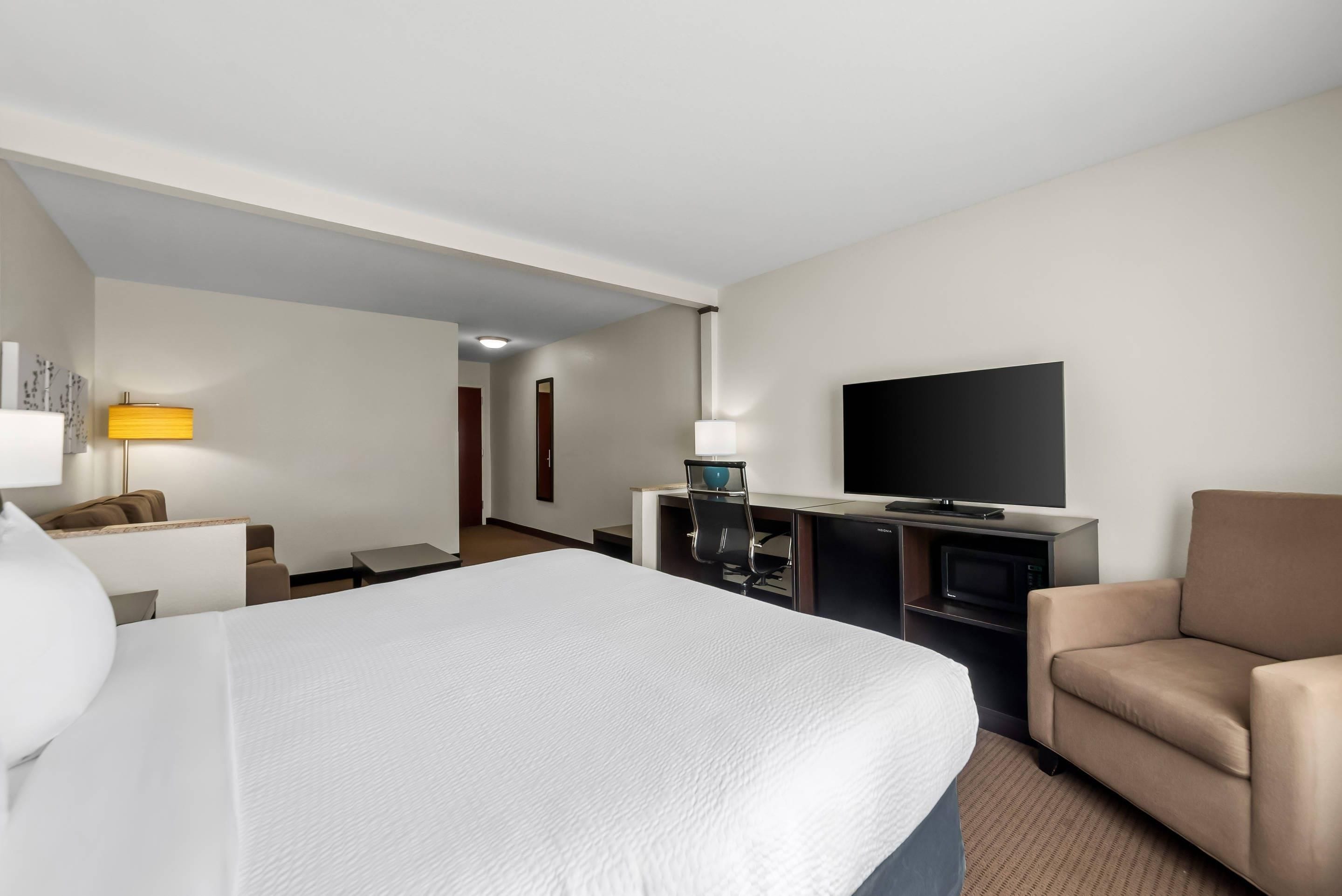 Ein Hotelzimmer mit Bett, Schreibtisch, Fernseher, Stuhl und Lampe.