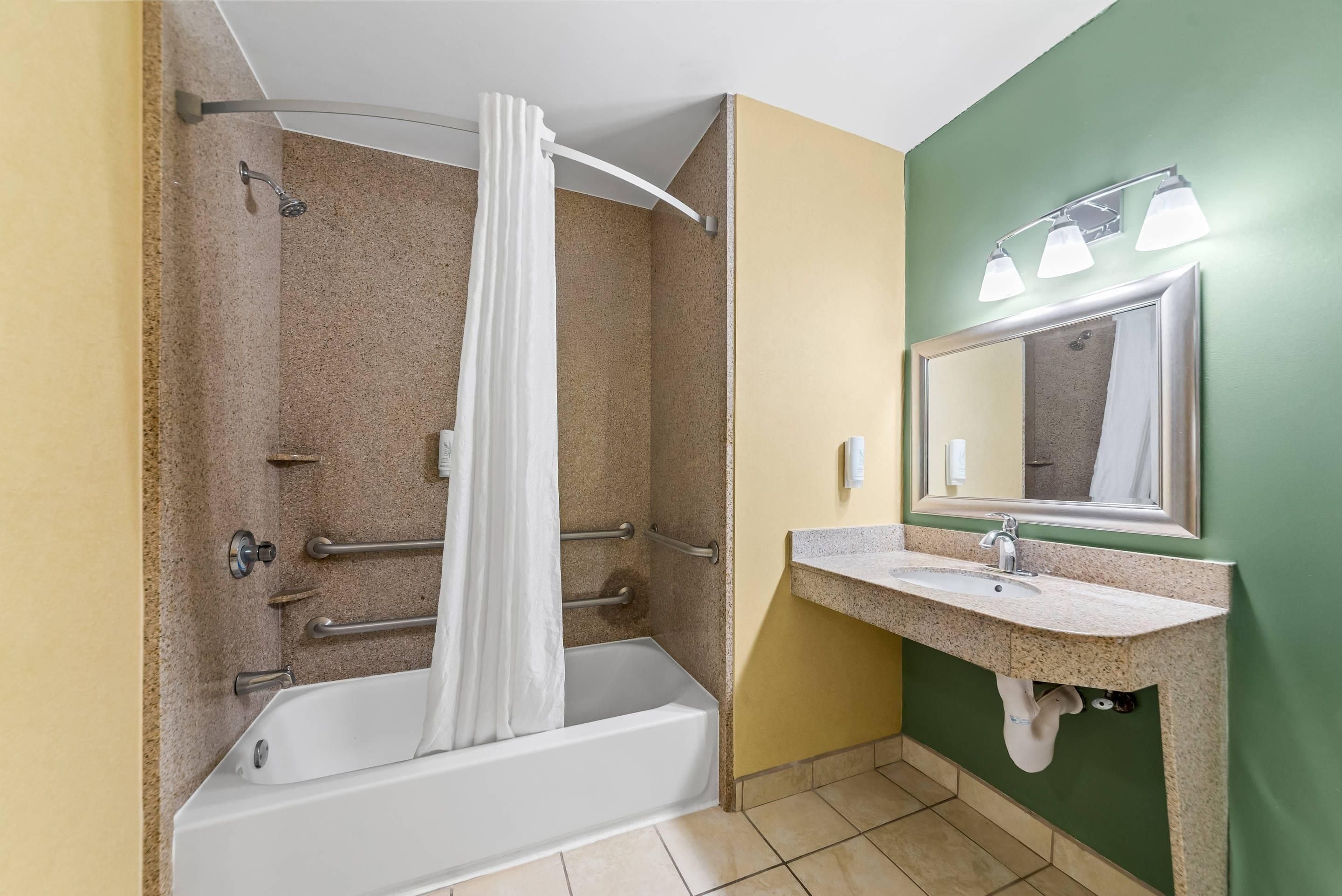 A bathroom with a bathtub, shower, and a sink with a mirror.