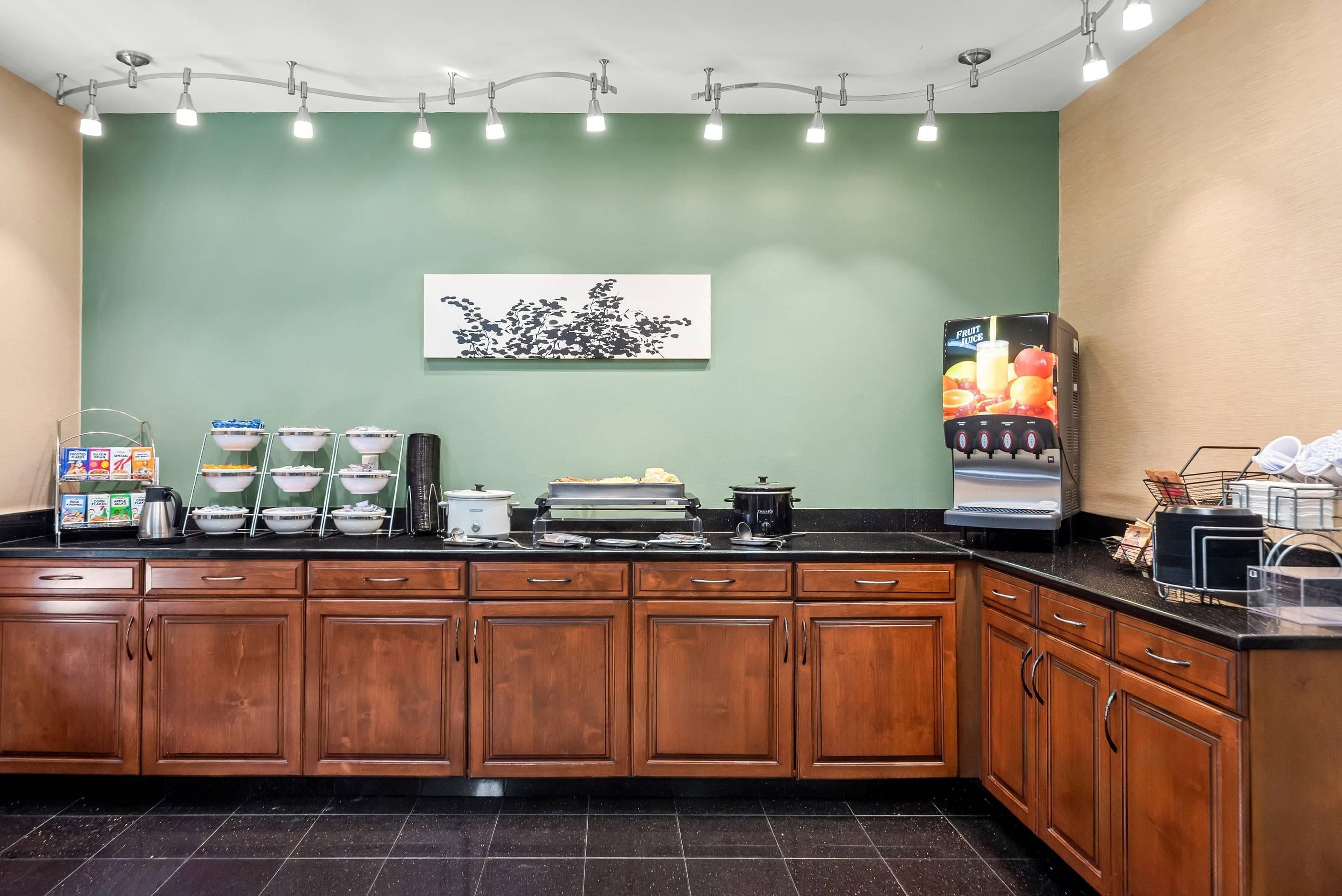 A kitchen with wooden cabinets, a coffee machine, and a fruit juice dispenser.