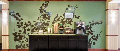 Un espace d’accueil agrémenté d’un mur végétal, d’une machine à café et d’un panneau indiquant « Dream Cup ».