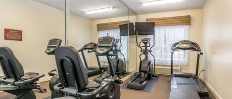 A fitness room with stationary bikes, treadmills, and a mirrored wall.