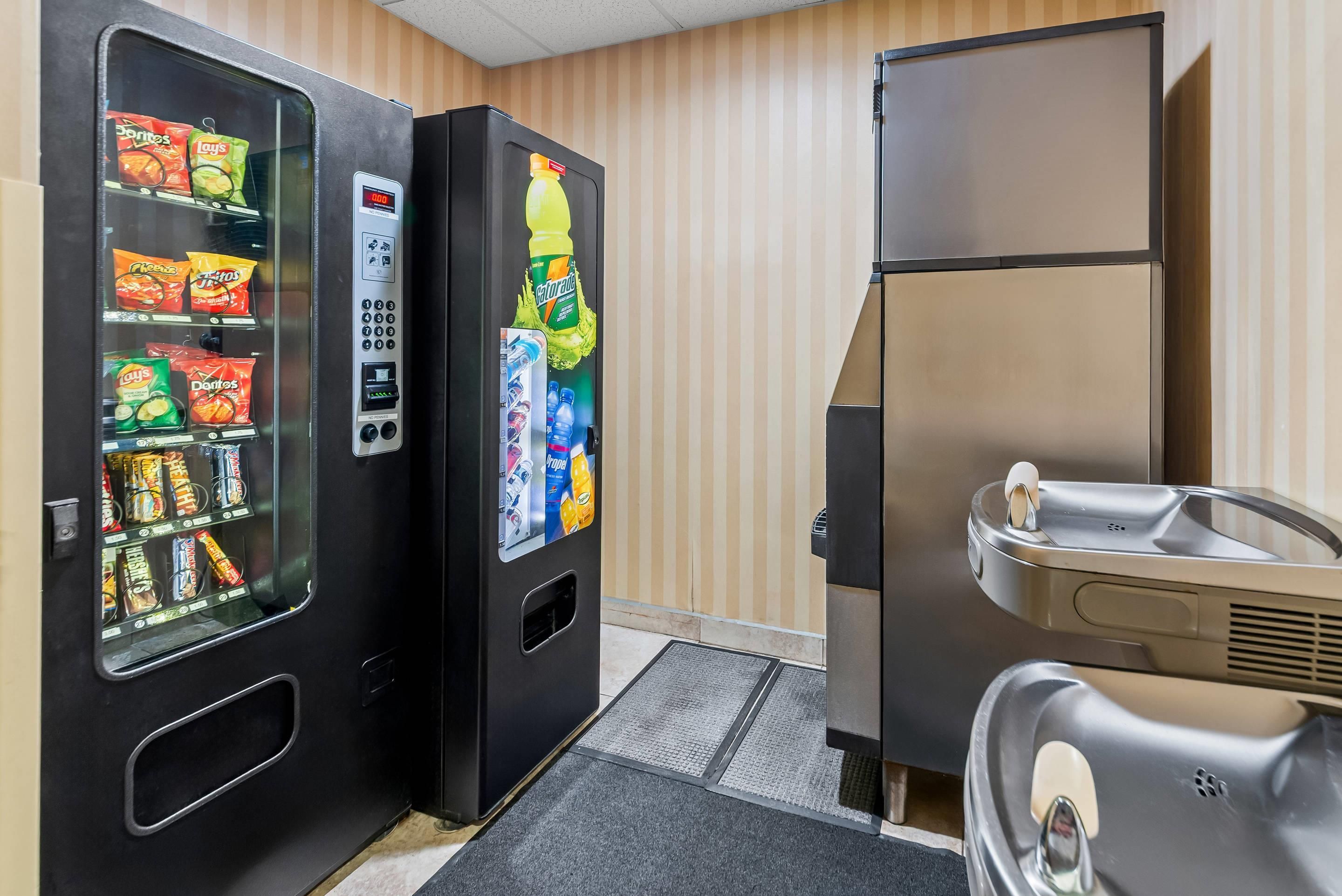 Una máquina expendedora con aperitivos y un refrigerador para Gatorade, junto a un refrigerador con dispensador de agua.