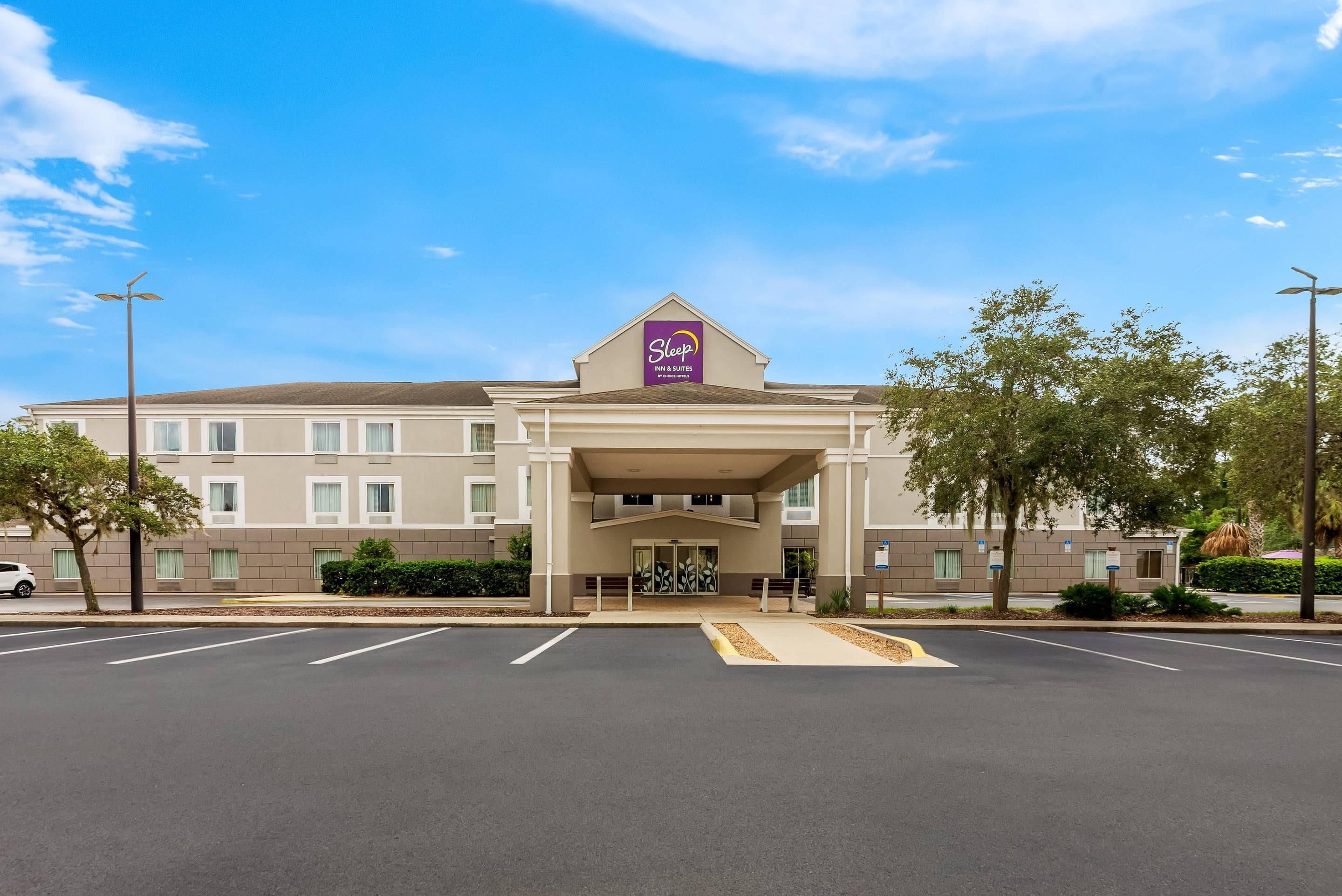 Un hotel con techo plano, entrada central y estacionamiento al frente.