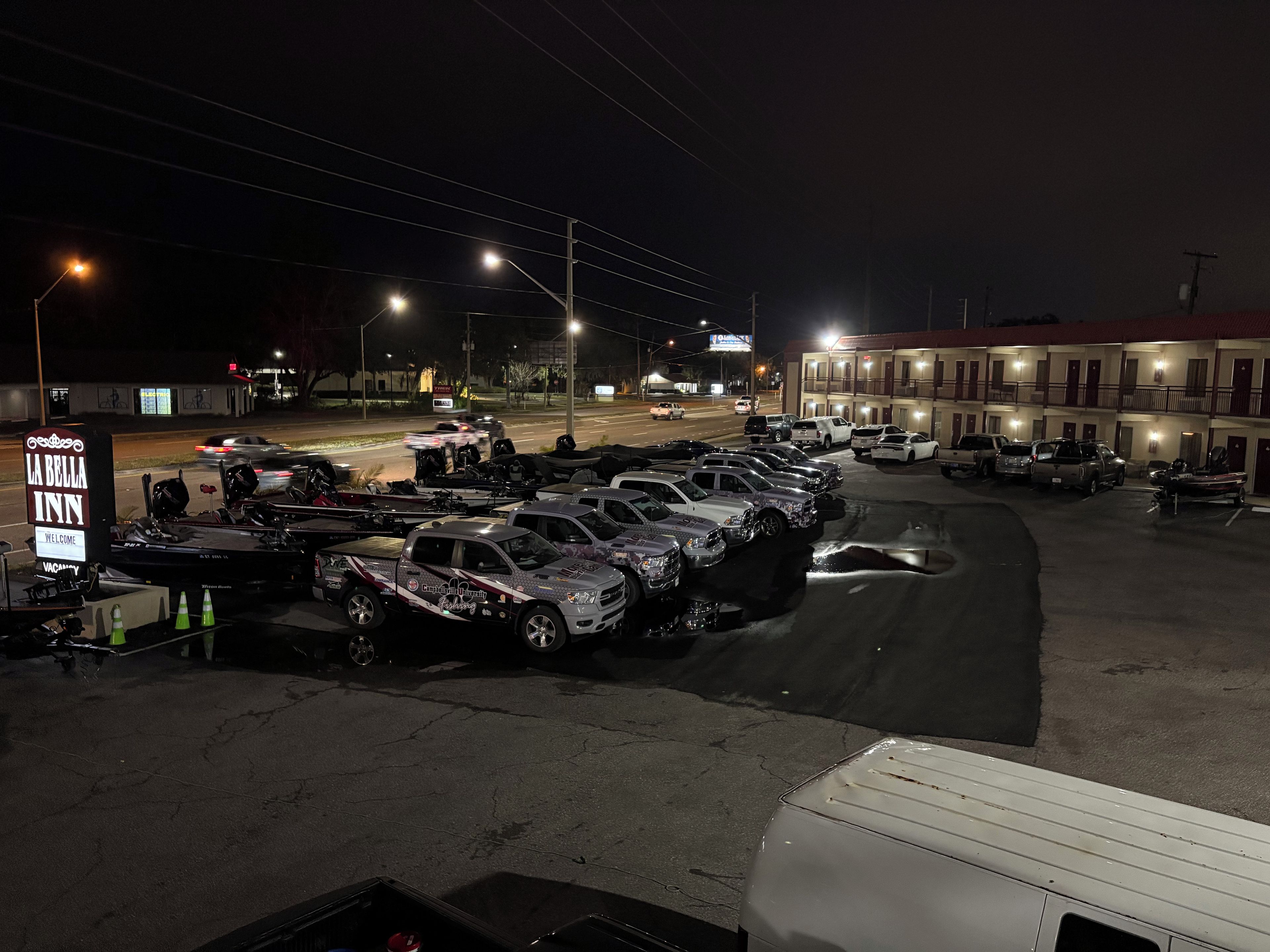 A parking lot with multiple vehicles, a sign for 'La Bella Inn,' and a building with multiple balconies.
