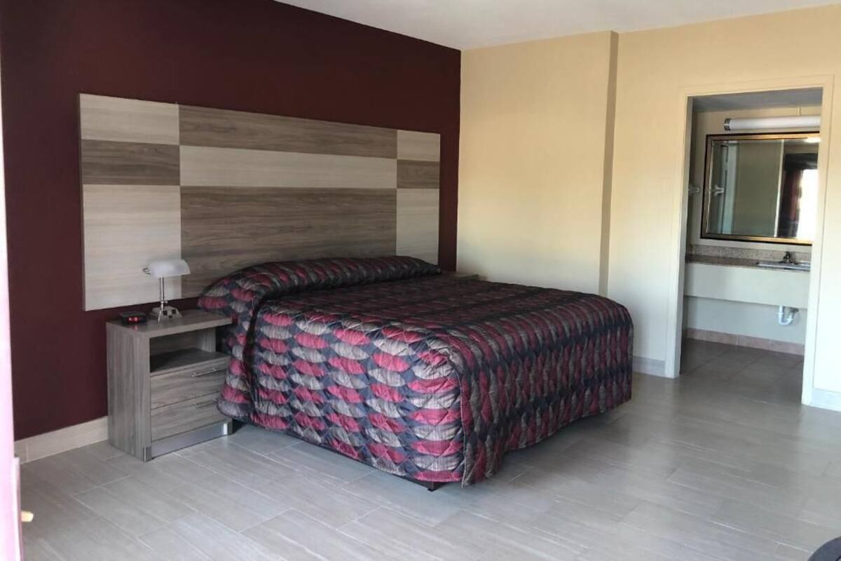 A bedroom with a bed, a nightstand, a mirror, and a wardrobe.